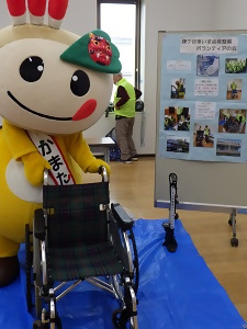 展示コーナーで車いすを押すかまたんの写真