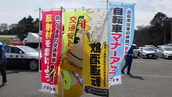 交通安全啓発ののぼりのすき間から覗くかまたんの写真