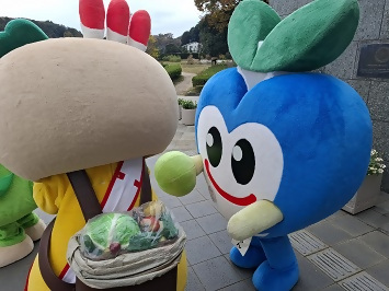 かまたんの背中のしょいかごの野菜を見つめているみのりちゃんの写真