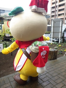 クリスマスバージョンの、サンタ帽をかぶり大きな靴下をしょいかごにぶら下げたかまたんの写真