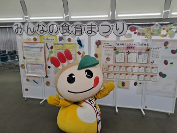 食育まつりの展示の前にいるかまたんの写真