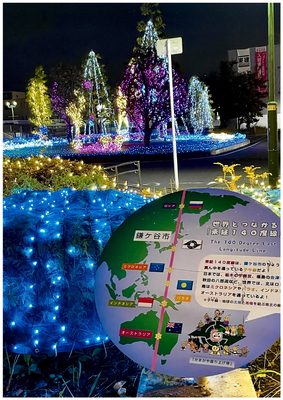 新鎌ヶ谷駅前広場で撮影されたイルミネーションと東経140度線の看板の写真です。