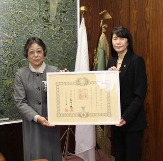 写真（章記を持つ今村喜和子さん（左）と芝田市長）