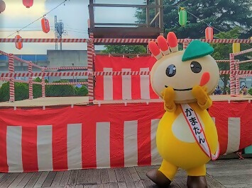 やぐらの前でポーズを決めるかまたんの写真