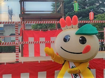 やぐらの前で盆踊りをするかまたんの写真
