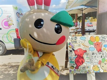 袋入りの梨を持つかまたんの写真