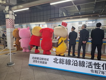 活性化トレインを見送る関係者とキャラクター達の写真