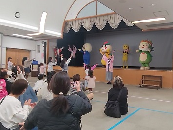 ダンスするキャラクター、参加者の子ども達と振り付けを教えるアテンドスタッフの写真