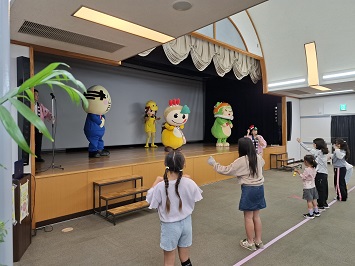 振り付け練習する参加者の子ども達とキャラクター達の写真