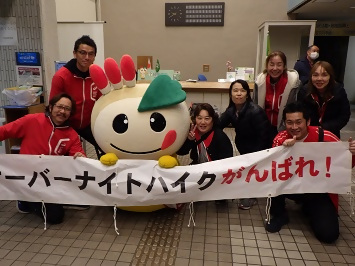 「オーバーナイトハイクがんばれ!」の横断幕を持って応援している、スタッフのみなさんとかまたんの写真