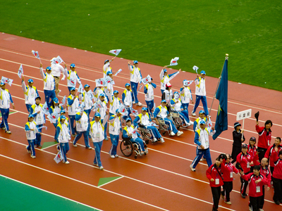 会場で選手たちが旗をかかげて歩いている様子（写真）