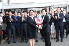 市役所前で職員から花束を受け取る芝田市長（写真）